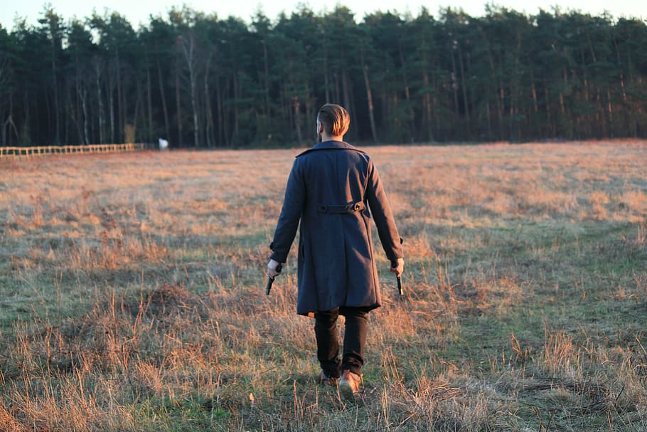 man, holding, two, guns, walking, grass field, daytime, move, back view, weapons