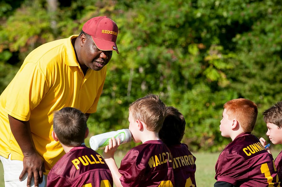 man coaching boys, daytime, coach, trainer, flag football, football, sport, game, competition, communication