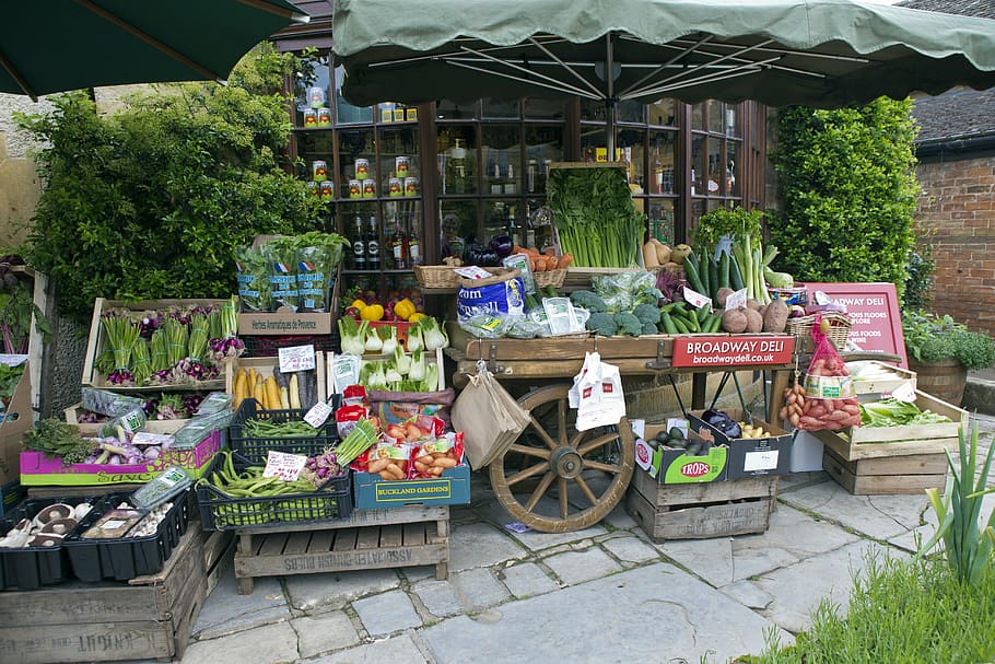 assorted vegetable stall, greengrocer's handcart, vegetable display, old wooden pallets and boxes, stone paving, shop window, broadway, cotswolds, uk, plant