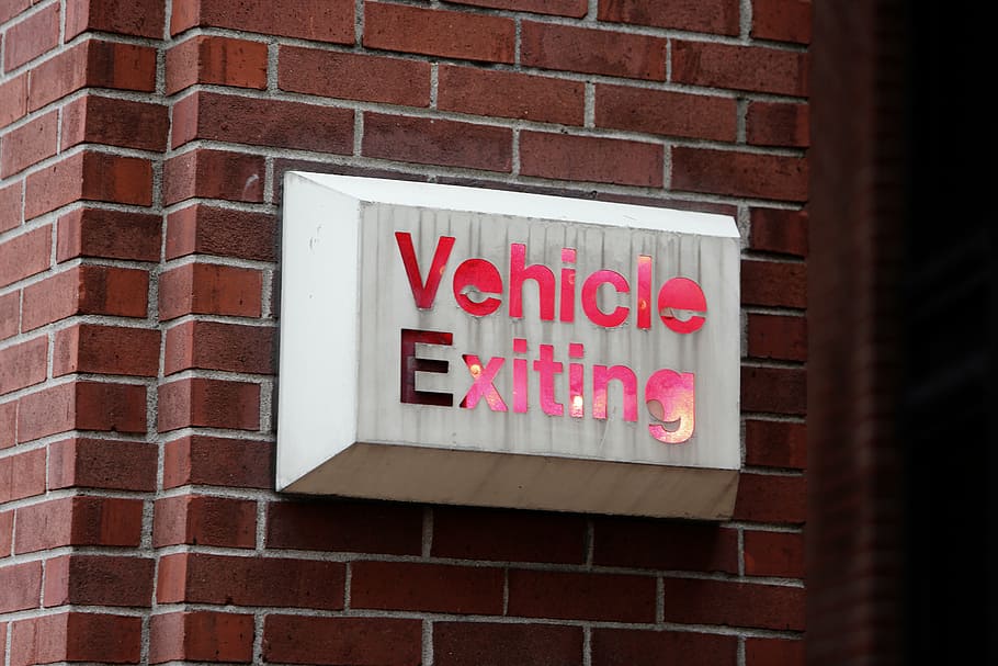 white, red, vehicle, exiting, signage, sign, bricks, exit, brick wall, text