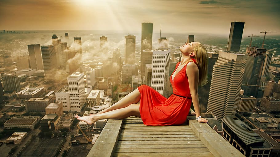 woman, wearing, red, sleeveless dress, sitting, wooden, cliff, across, high, rise buildings