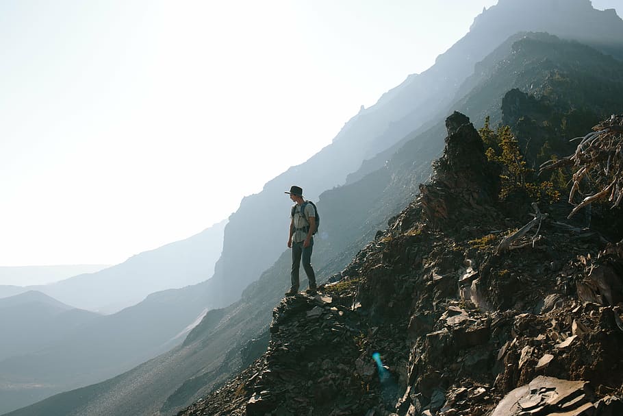 man, standing, cliff, peak, mountain, daytime, hiking, trekking, mountains, cliffs