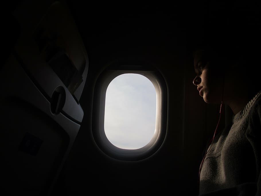 person, sitting, inside, aircraft, window, woman, wearing, gray, sweatshirt, taking