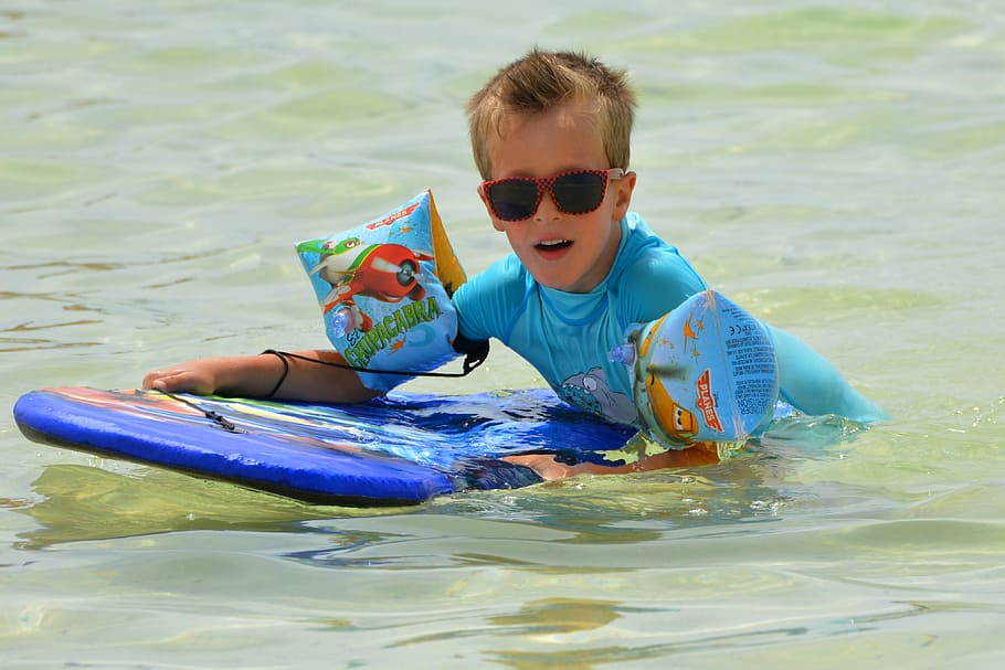 chico, sosteniendo, azul, tabla de surf, agua, niño, personas, gafas de sol, correas, protección uv