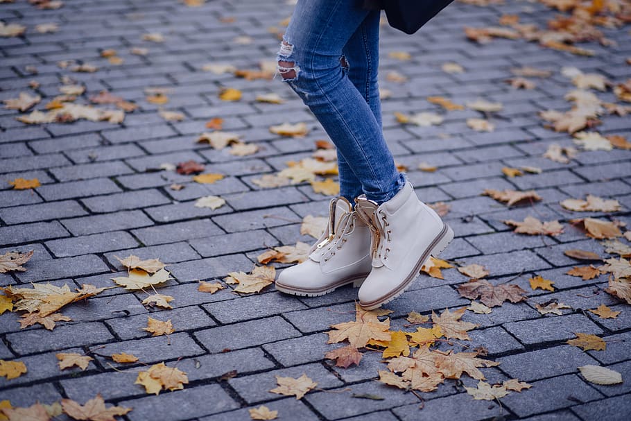 mulher, vestindo, marrom, botas de couro, folhas de outono, tijolo, cimento, paralelepípedo, concreto, folhas secas