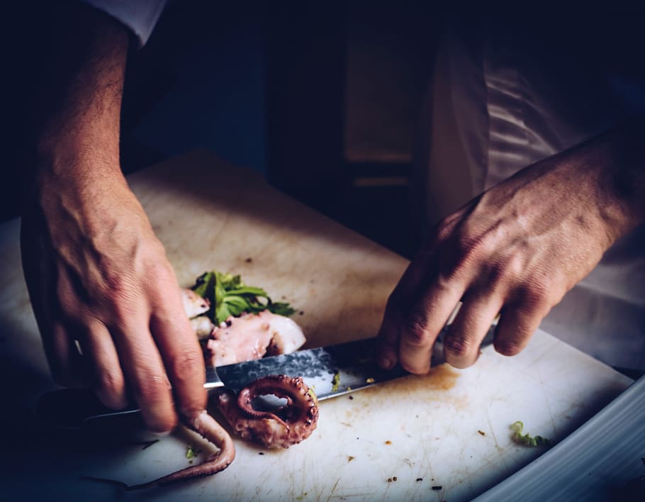person slicing squid, hands, cutting, cooking, knife, chopping board, octopus, chef, food and drink, human hand