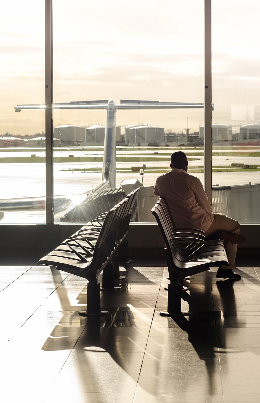 man, white, dress shirt, pants, sitting, gang chair, terminal, gate, waiting, airplane