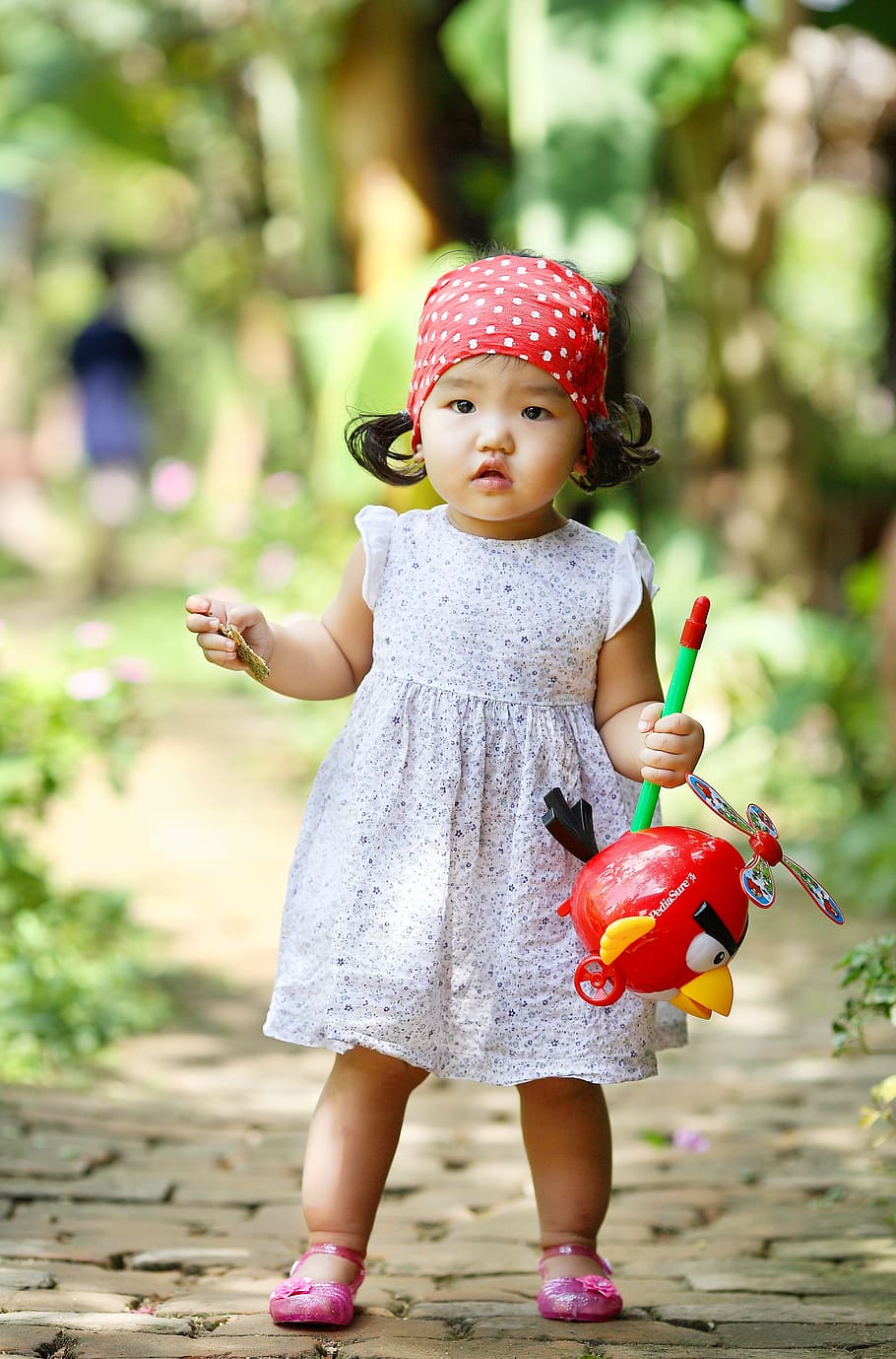 girl, white, sleeveless dress, standing, paver brick, daytime, red, Angry Bird, toy, dress