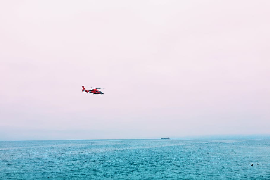 red, helicopter, hovering, body, water, flying, daytime, sea, ocean, blue
