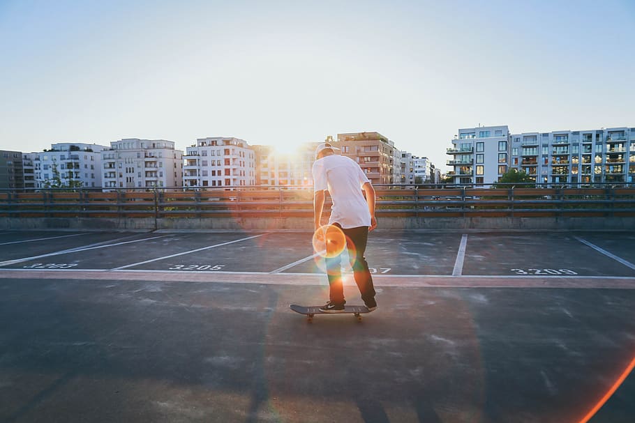 man, wearing, white, t-shirt, black, pants, standing, skateboard, daytime, buildings