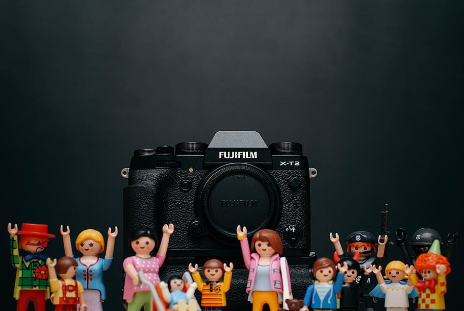 black, fujifilm dslr camera, surrounded, action figures, surface, fujifilm, camera, photography, toy, display
