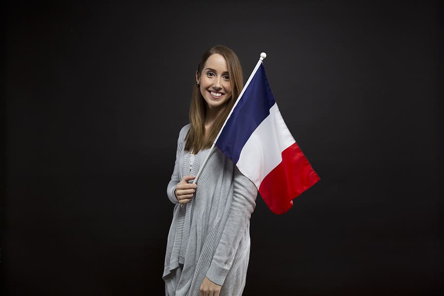 woman, wearing, gray, cardigan, holding, red, blue, white, flag, flags